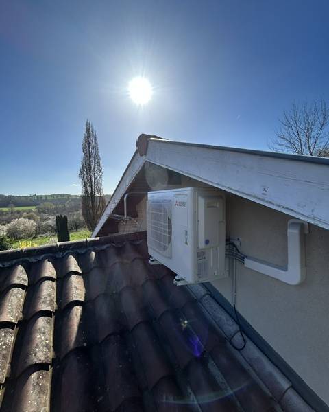 Unité extérieure de climatisation réversible Mitsubishi Electric posée en pignon sous débord de toit, en Drôme