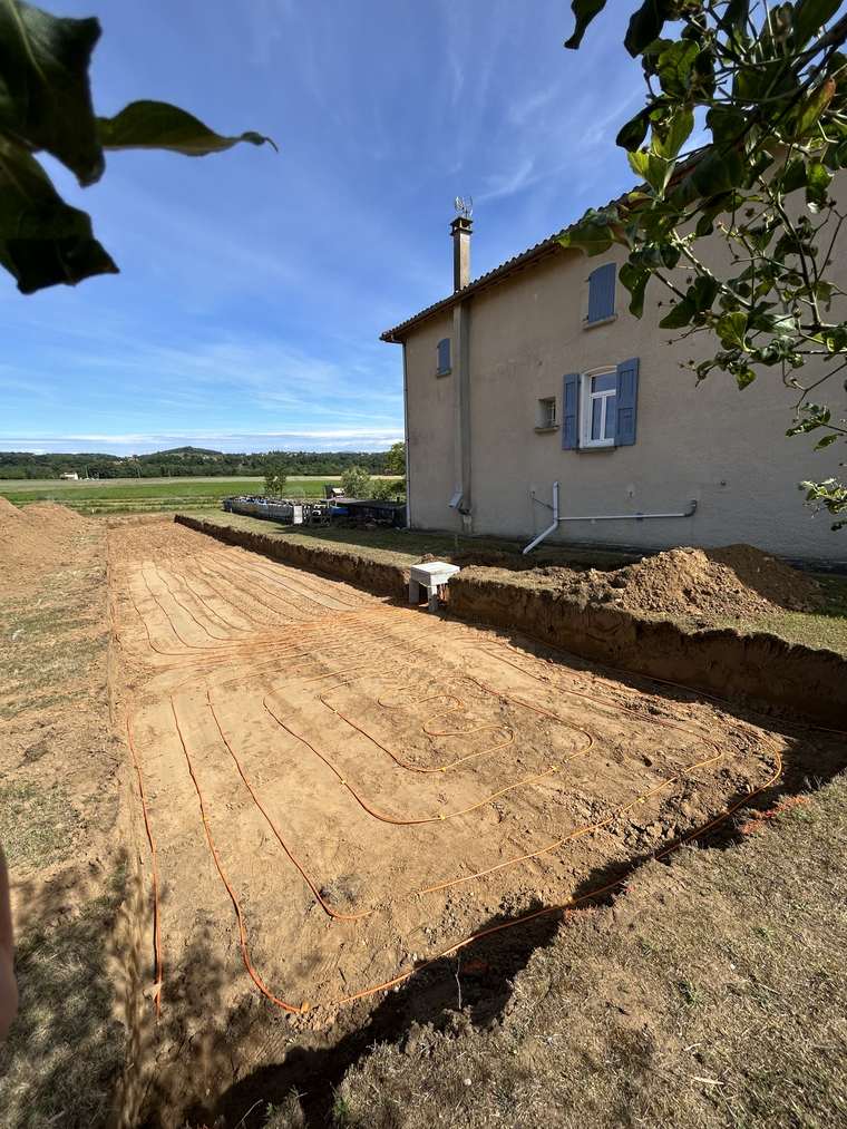 Capteurs géothermiques horizontaux déroulés en tranchée devant une maison